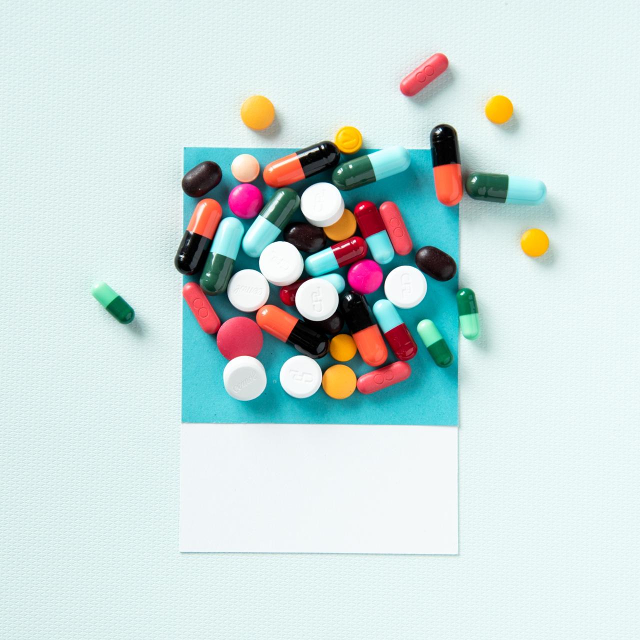 An assortment of coloured tablets and capsules spilling out of a paper envelope.