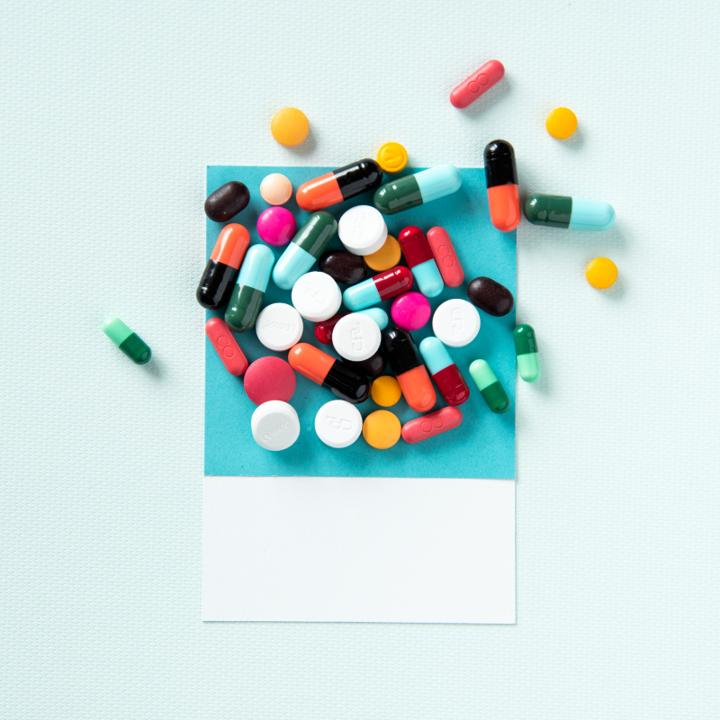 An assortment of coloured tablets and capsules spilling out of a paper envelope.