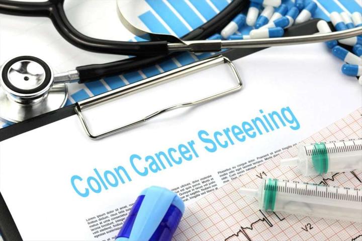 A clipboard headed “Colon Cancer Screening” lying beside a stethoscope, syringes and printed test results.
