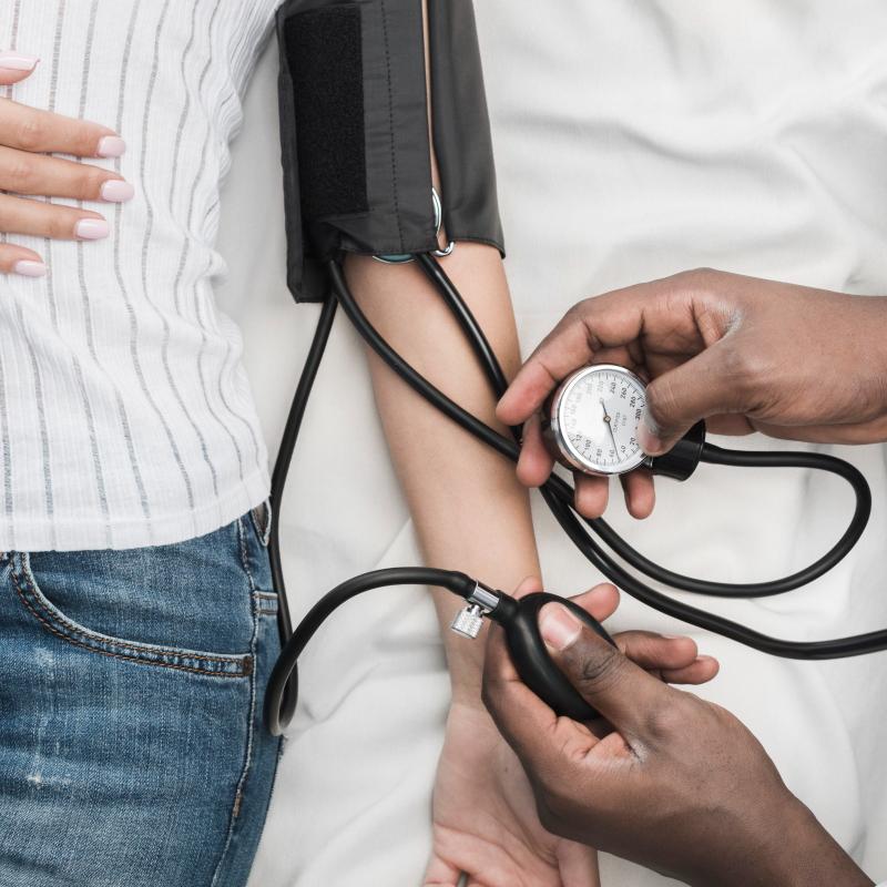A nurse taking a woman’s blood pressure with a cuff and dial, photographed from above.
